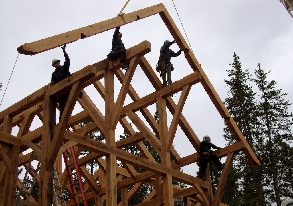 timber frame rafter being set with crane